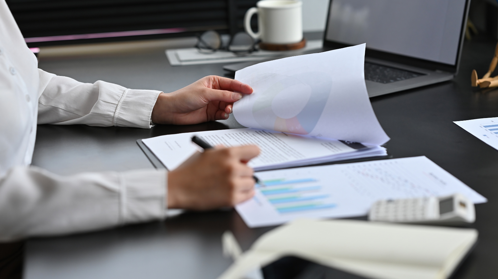 Person at a desk turning pages of a printed financial report while reviewing concentrated stock positions